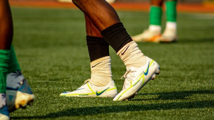 Soccer players training on a grass field in bright cleats and socks. Soccer players training on a grass field in bright cleats and socks.