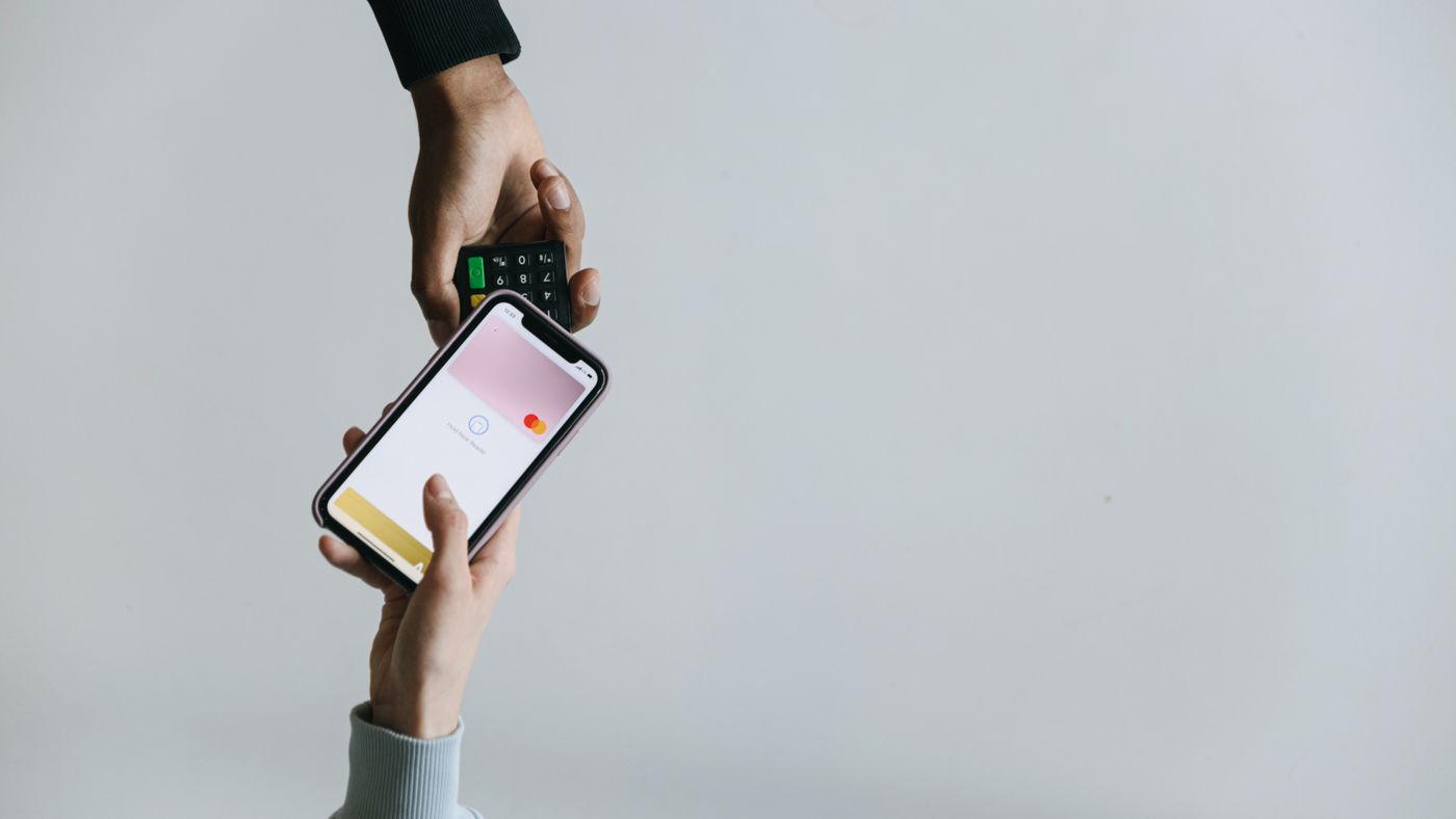 Mani che usano smartphone e terminale per pagamento senza contanti