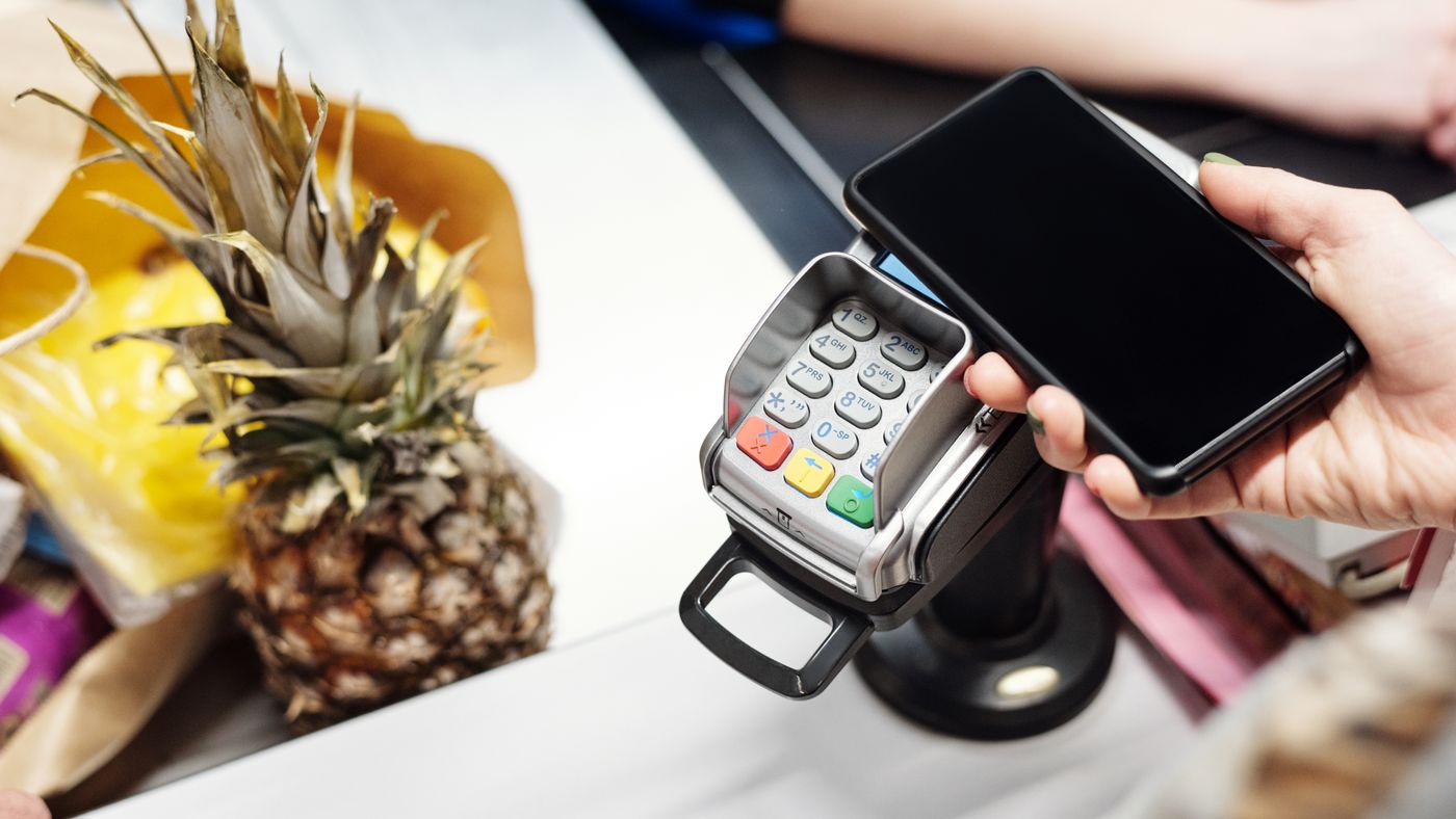 Cliente usa smartphone per pagamento contactless con un ananas sul banco