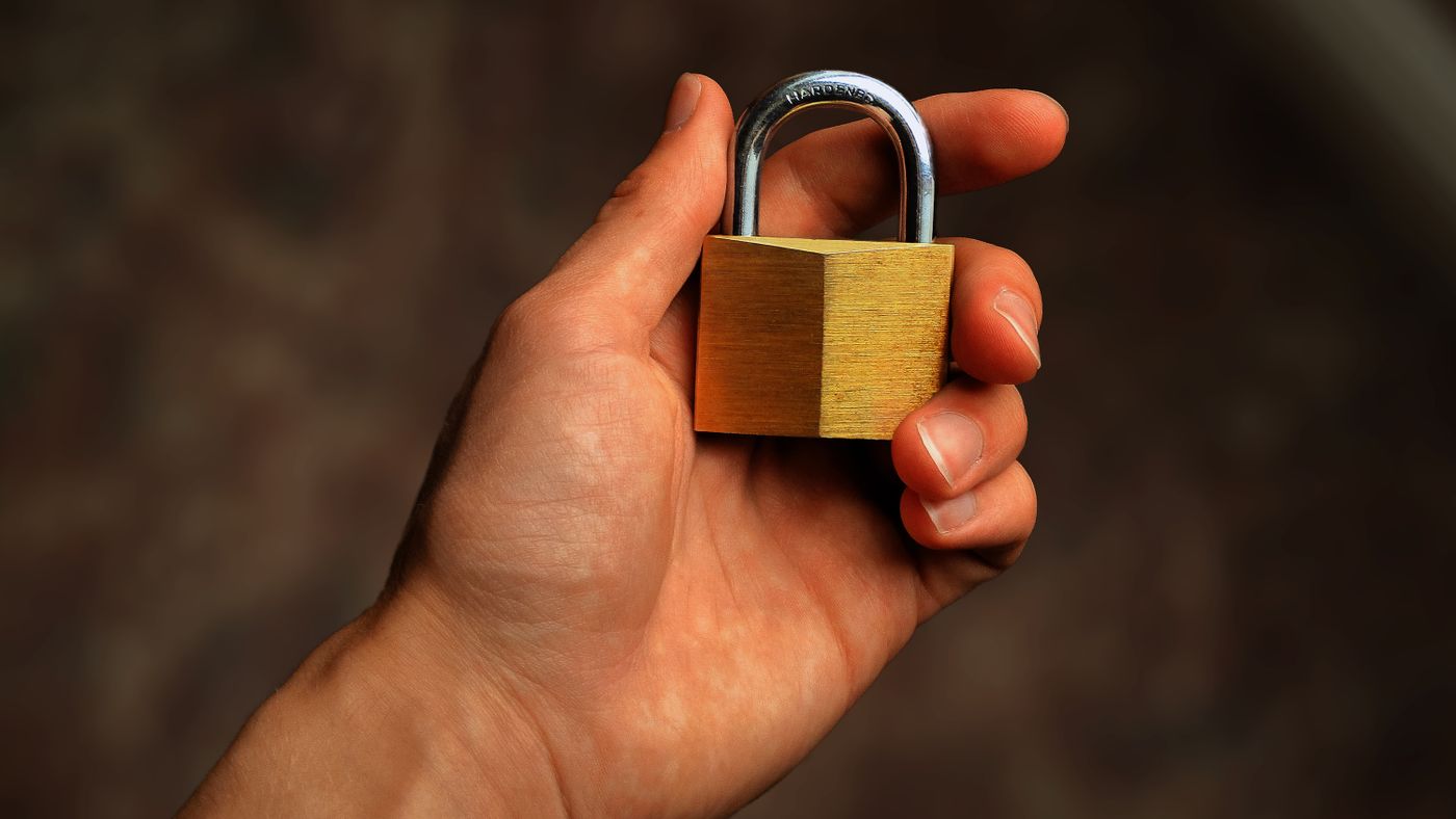Mano che tiene un lucchetto di ottone, simbolo di sicurezza