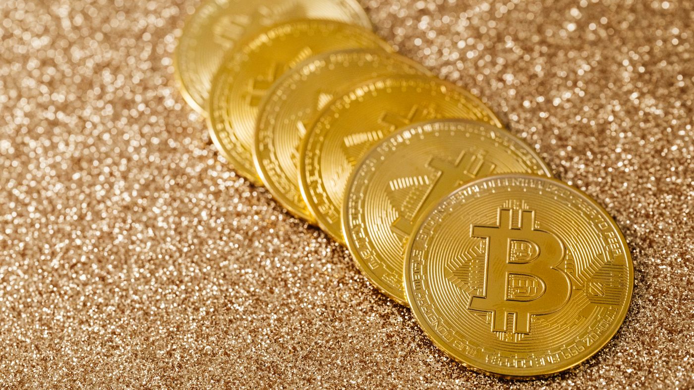 Pila di monete d'oro Bitcoin su sfondo glitterato dorato