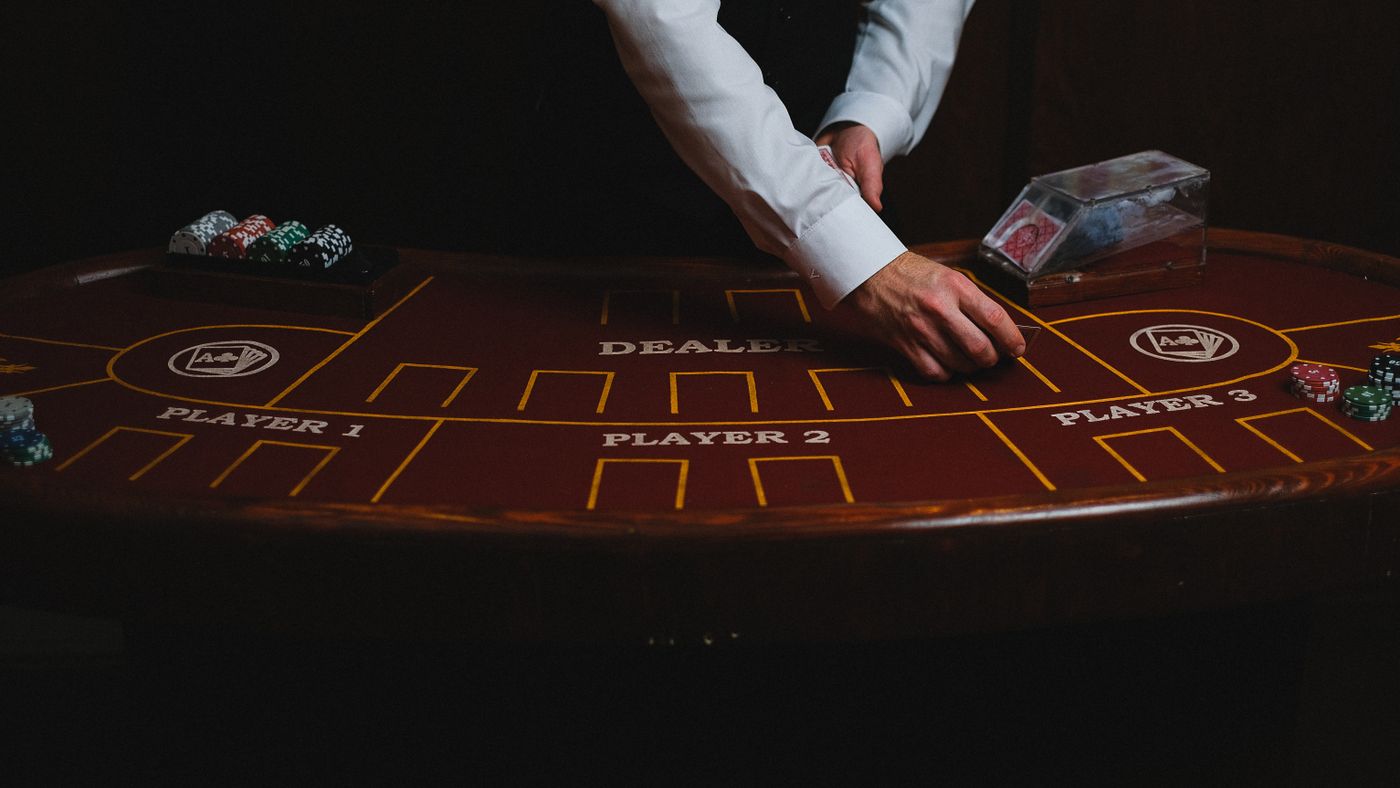 Croupier distribuisce carte su un tavolo da casinò poco illuminato