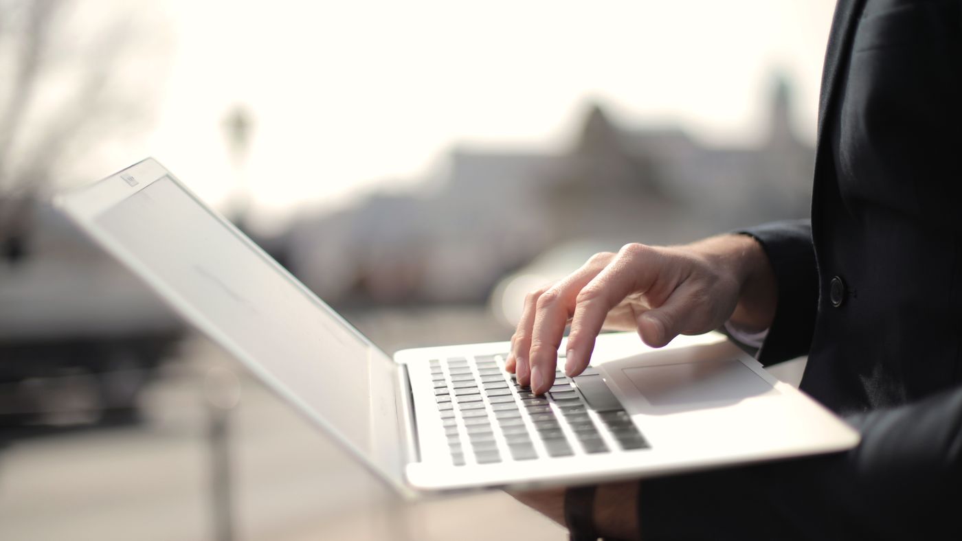 Professionista che digita su un laptop all'aperto, lavoro da remoto