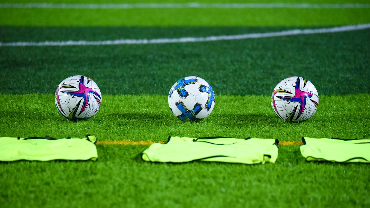 Tre palloni da calcio e casacche su un campo verde a Rawalpindi